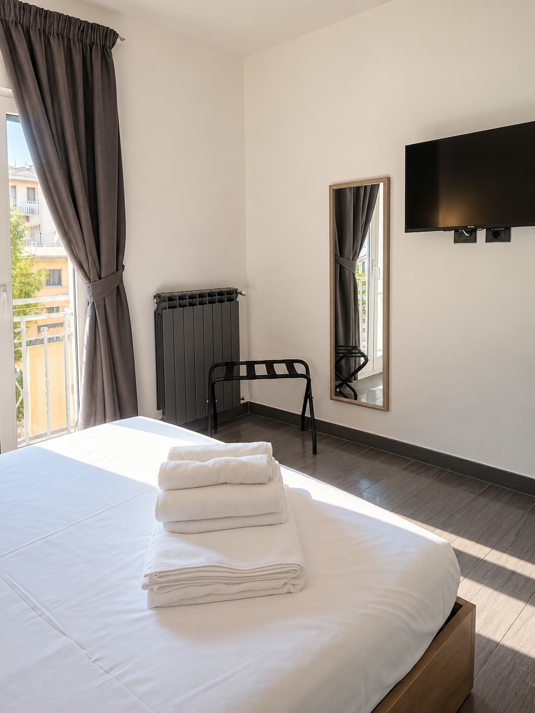 Camera matrimoniale con TV, specchio, portavaligie e porta finestra sul balconcino